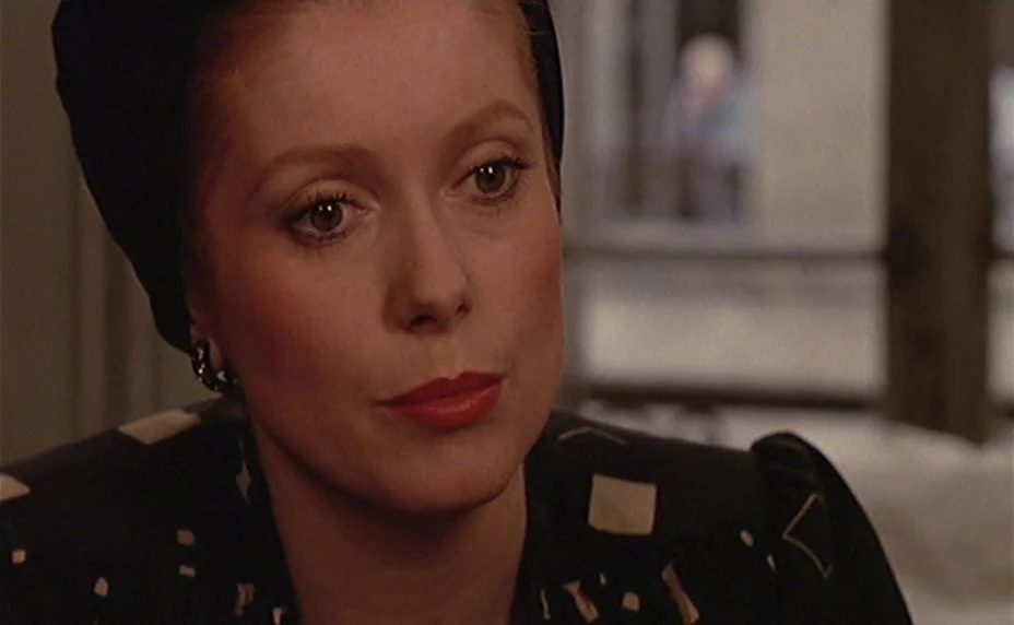 The Last Metro (1980) movie still: closeup — A woman stands in a softly lit interior space with a blurred background area. She gazes slightly…