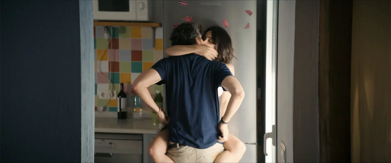A Hipster in Rural Spain (2024) movie still: medium — A residential kitchen features colorful wall tiles, a silver refrigerator, and a countertop. A…