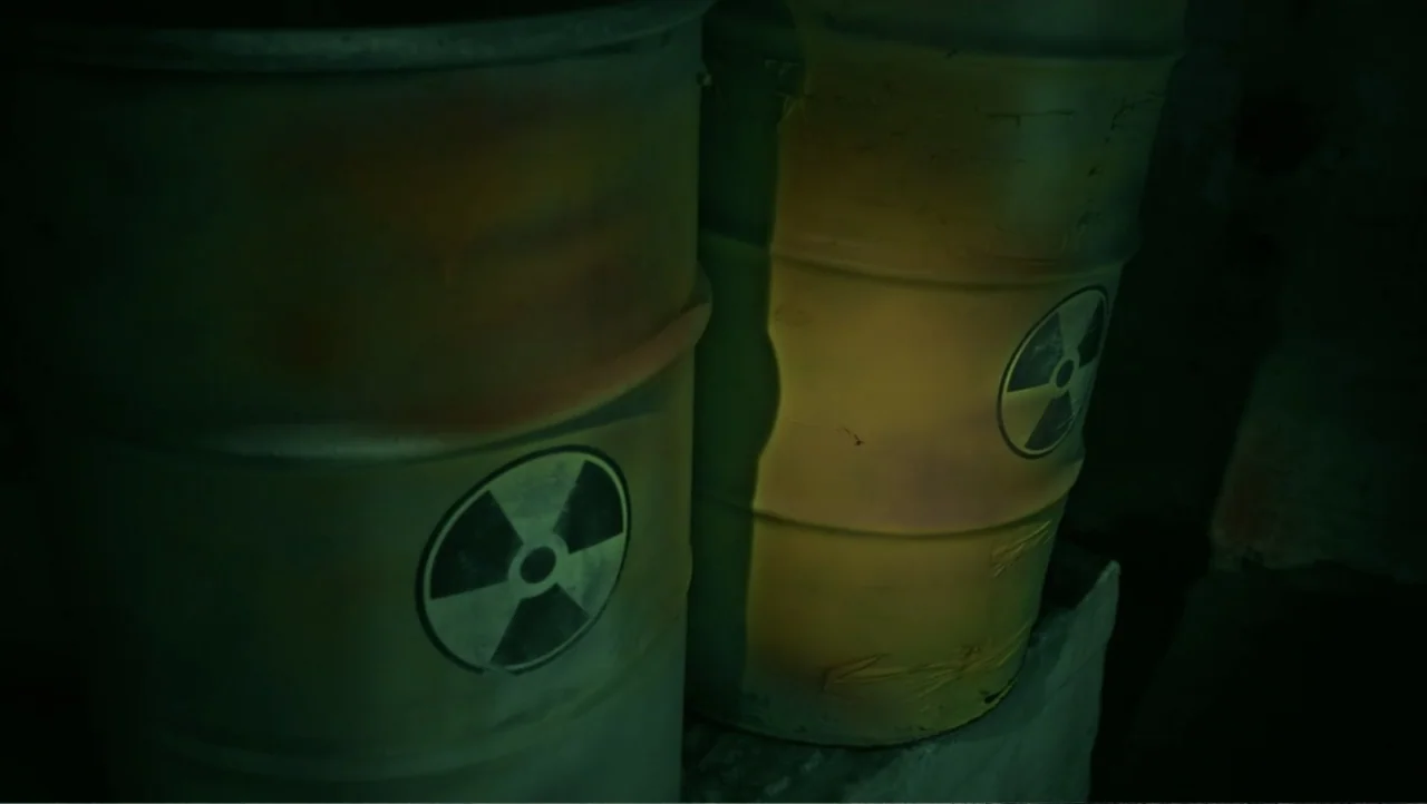 Shadow Master (2022) movie still: medium — Two metal drums marked with radioactive symbols sit side by side in the dark. The containers are slightly…