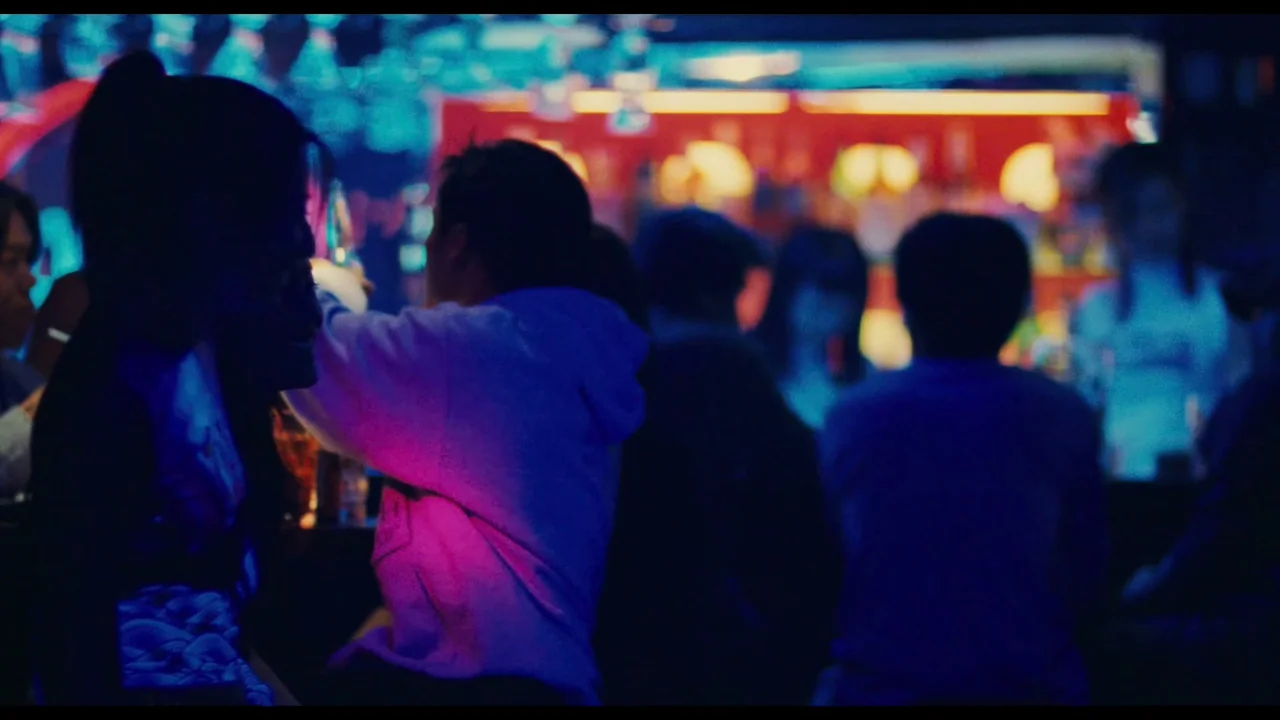 Millennium Mambo (2001) movie still: medium — A dimly lit counter area features patrons sitting in a vibrant nightclub environment. A woman and a…