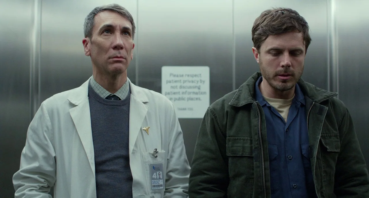 Manchester By The Sea (2016) movie still: medium — A metallic, austere elevator interior features a polite patient privacy notice on the rear wall.…