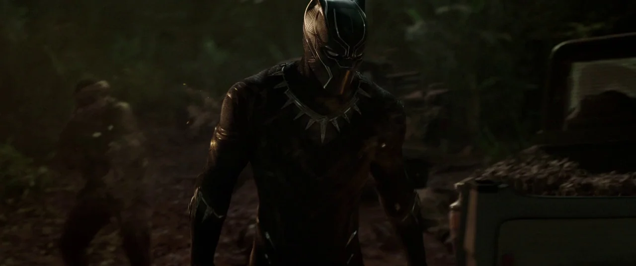 Black Panther (2018) movie still: medium — A dense, shadowed tropical environment filled with dark vegetation and low-hanging tree branches. A…