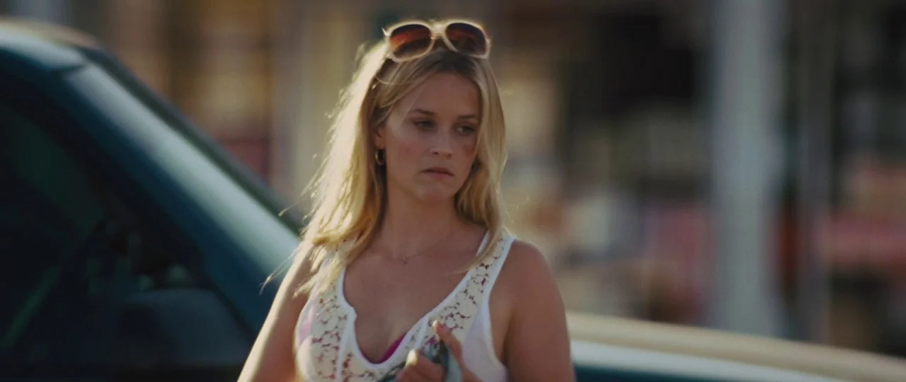 Mud (2012) movie still: medium — An outdoor location during the day shows a woman near a car. She stands by a teal vehicle while holding something…