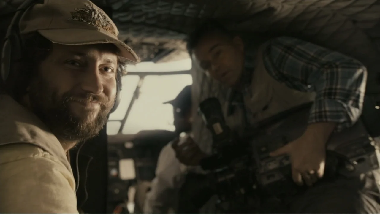 The Dinosaur Project (2012) movie still: medium — The interior of a helicopter cabin features quilted gray upholstery and a large cockpit window. A…
