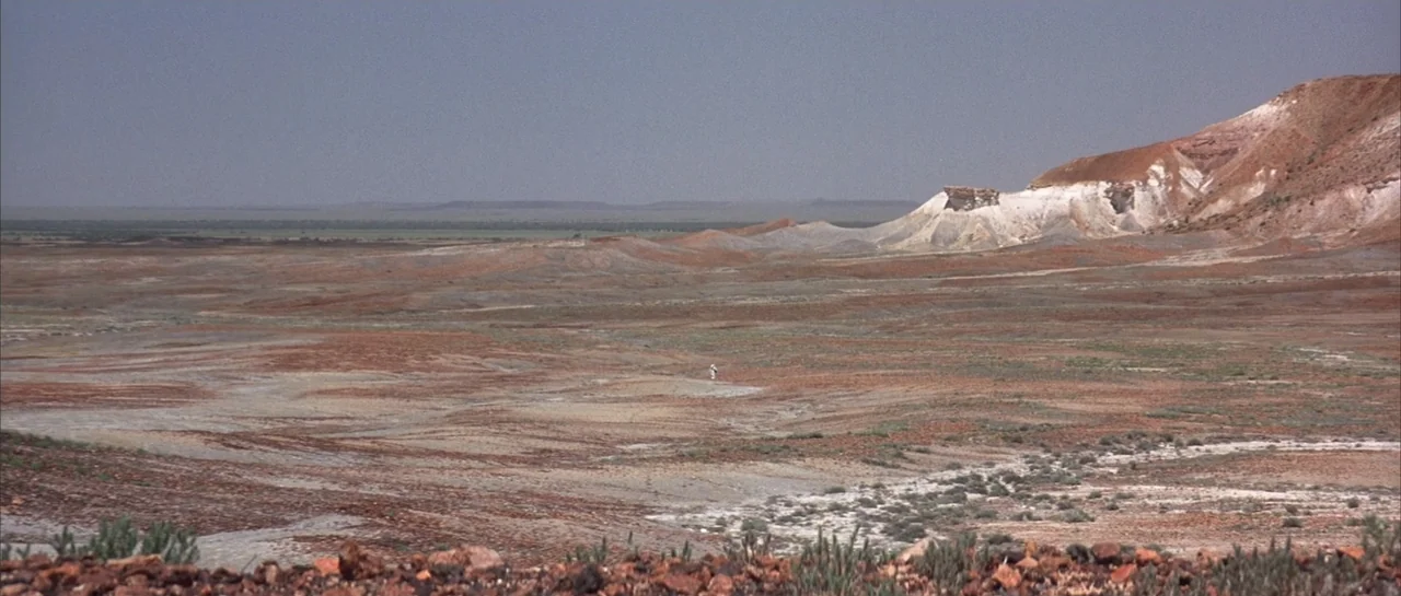 The Adventures of Priscilla, Queen of the Desert (1994) movie still: establishing — An arid desert expanse features low rolling hills and exposed…