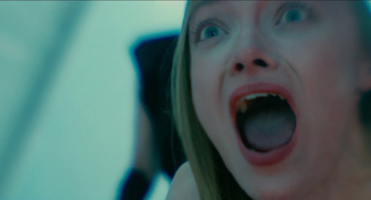 Trim Season (2023) movie still: closeup — A close-up view shows a woman's face against a blurred light-blue background. She is screaming with her…
