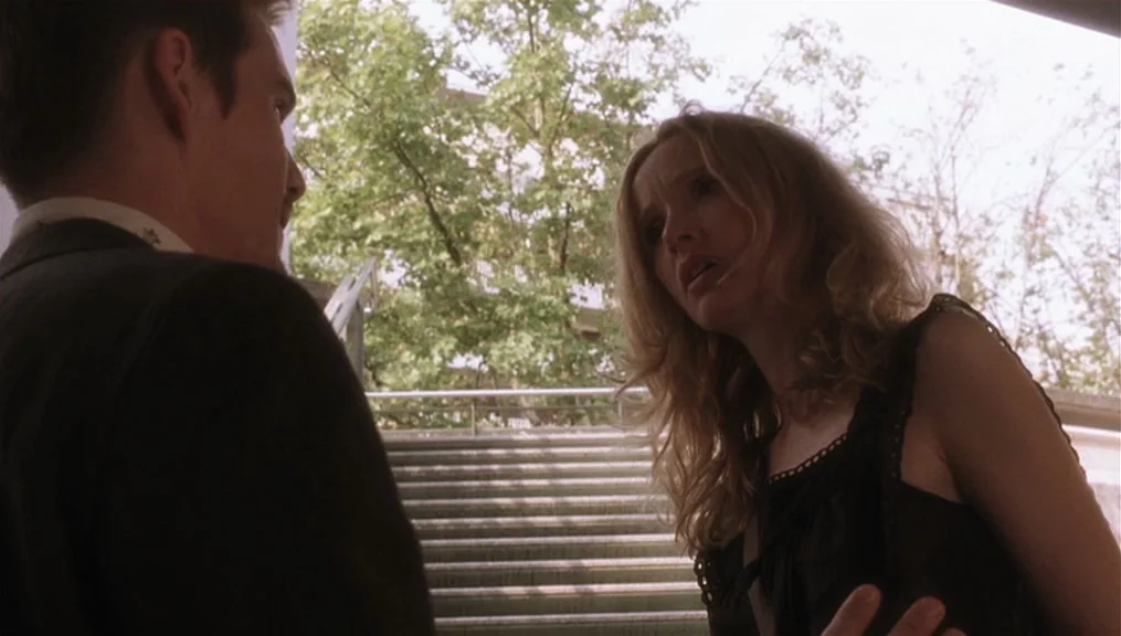 Before Sunset (2004) movie still: medium — An outdoor concrete staircase sits in front of green trees and building architecture. A woman stands…
