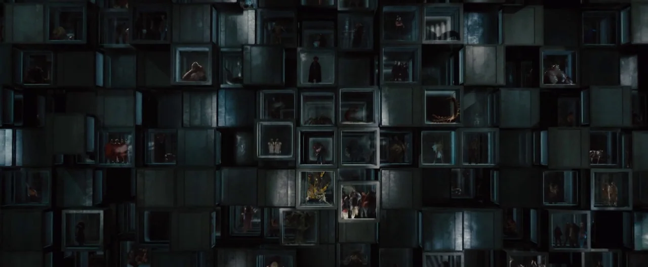 The Cabin In The Woods (2012) movie still: wide — A dark, grid-like wall is composed of numerous small, illuminated glass-fronted metal storage…