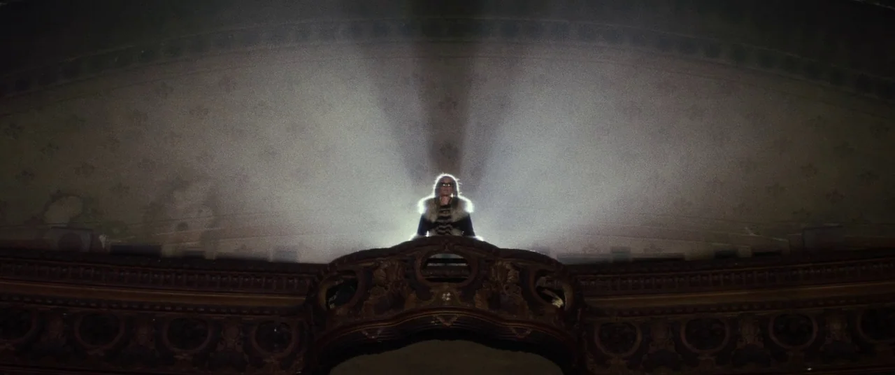 Lords Of Salem (2013) movie still: wide — A dark, ornate theater balcony features curved woodwork and vintage-patterned wallpaper. A person wearing…