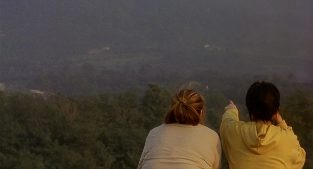 Barking Dogs Never Bite (2000) movie still: medium — Two women stand on a high grassy ridge overlooking a vast green valley. The person on the right…