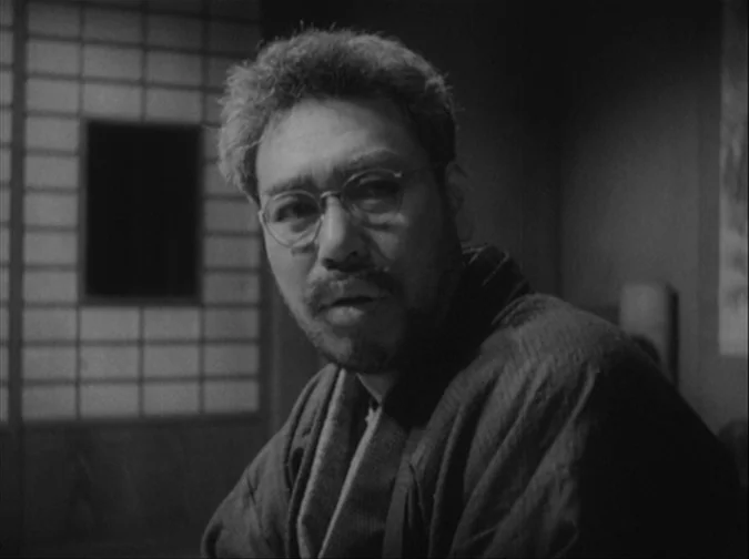 Drunken Angel (1948) movie still: medium — A Japanese room features a shoji screen door with a grid pattern. A man in a dark kimono gazes off-camera…