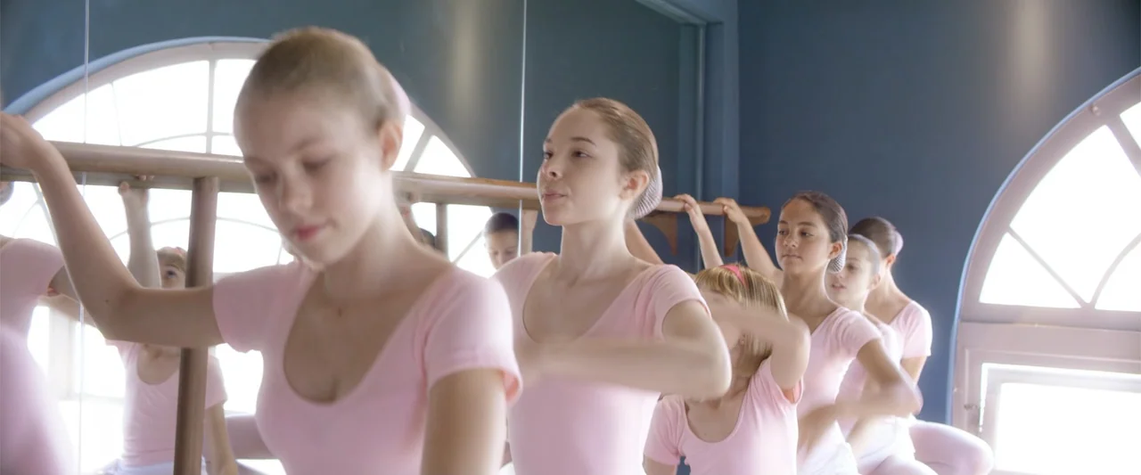 Dirty Little Secret (1998) movie still: medium — A well-lit dance practice space features a wooden ballet barre and large arched windows. Several…