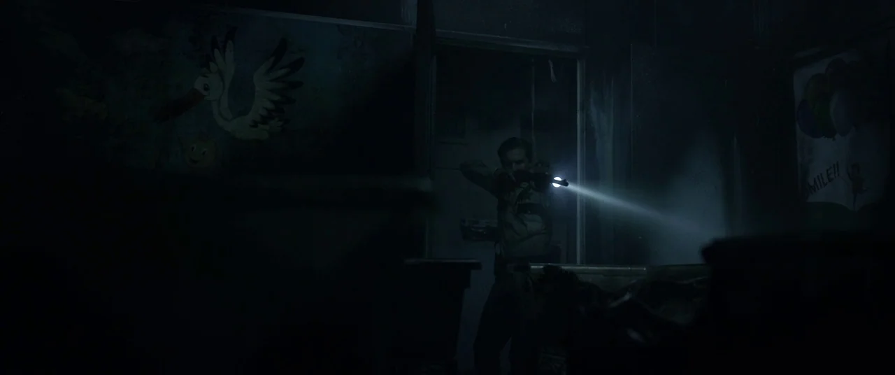 The Void (2016) movie still: medium — A darkened, desolate hospital corridor features faded wall murals of a stork carrying a baby. A male officer…
