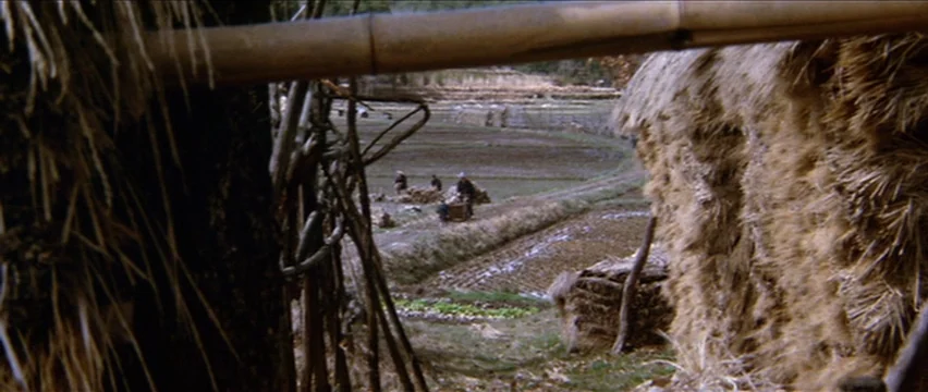 Lone Wolf and Cub: White Heaven in Hell (1974) movie still: wide — Rural terraced agricultural fields are framed between two thatched structures…