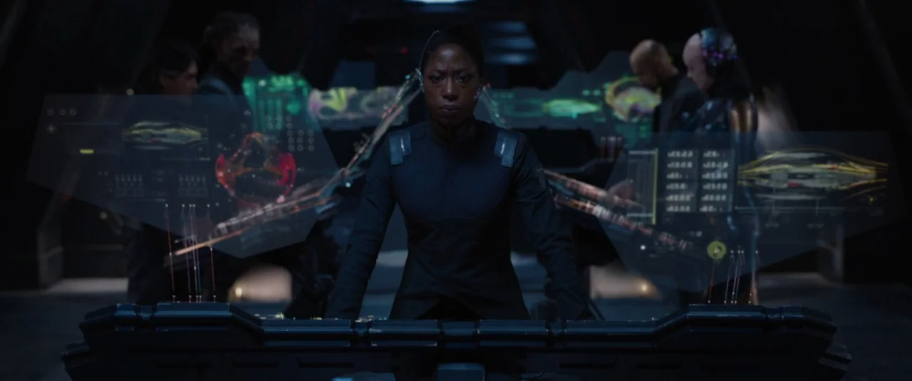 Jupiter Ascending (2015) movie still: medium — A dimly lit futuristic starship command center features glowing holographic displays floating over…