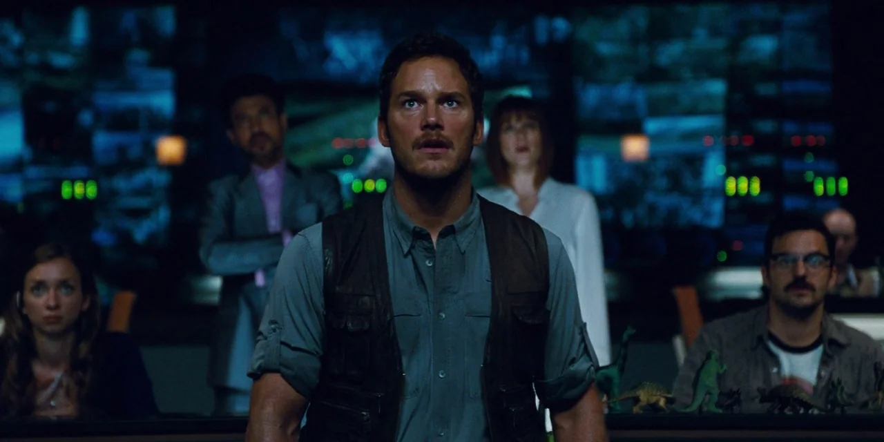 Jurassic World (2015) movie still: medium — A high-tech control room with dark surroundings filled with glowing display screens. A man stands in the…