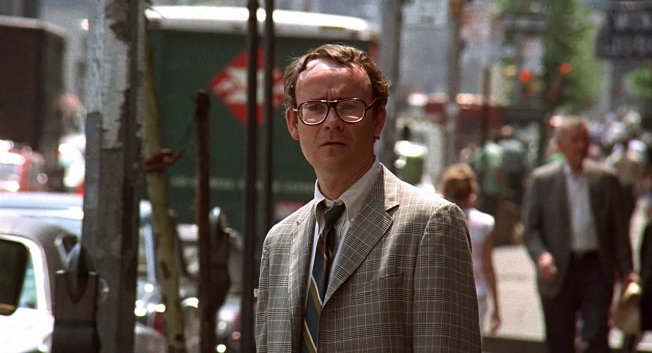 Taking Off (1971) movie still: medium — A bustling city sidewalk features a man centered in the foreground amidst urban traffic. The man wearing a…