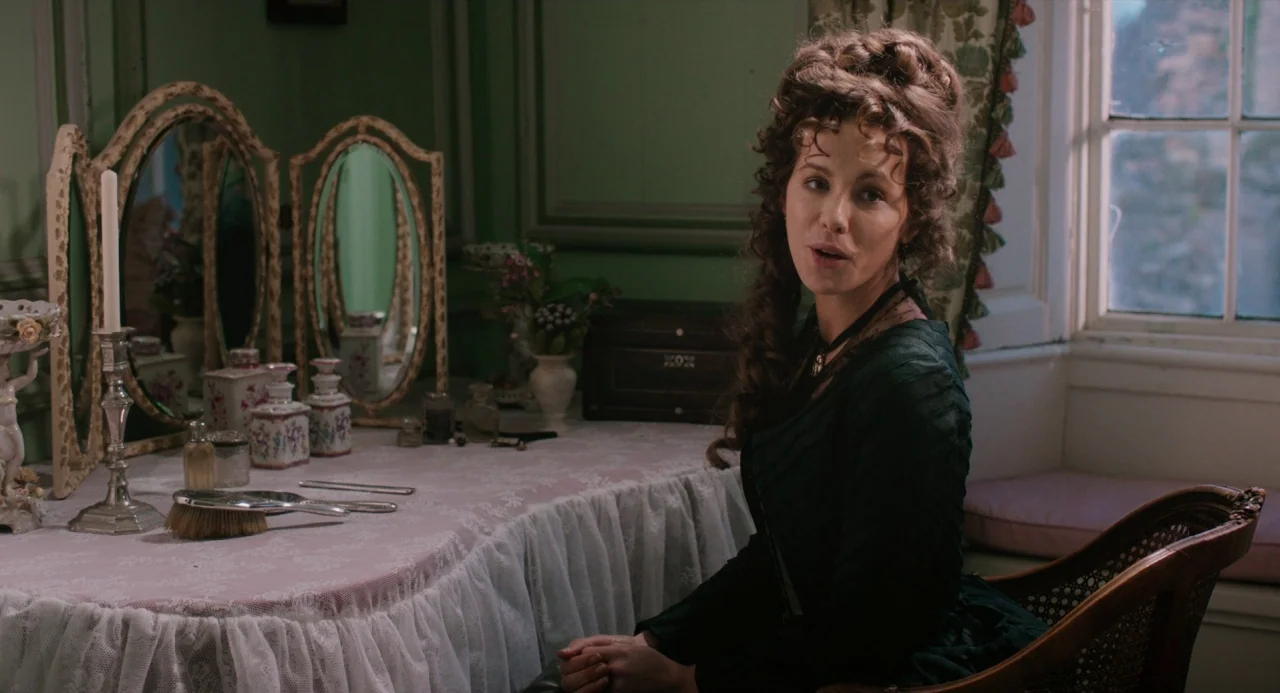 Love and Friendship (2016) movie still: medium — A Victorian-era room with a lacy white vanity table topped with antique cosmetic items. A woman in…