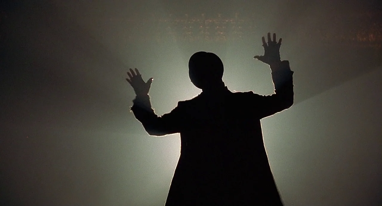 Chicago (2002) movie still: fullbody — A dark, atmospheric stage filled with light haze and concentrated beams of light. A person stands in the…