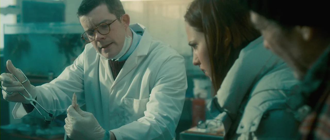 Grabbers (2012) movie still: medium — A sterile laboratory setting features glassware and medical equipment in the background. A scientist inspects…