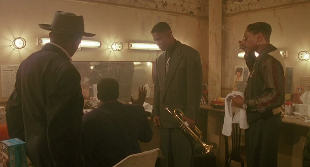 Mo’ Better Blues (1990) movie still: medium — A cluttered backstage dressing room with vanity mirrors and exposed fluorescent lighting fixtures.…