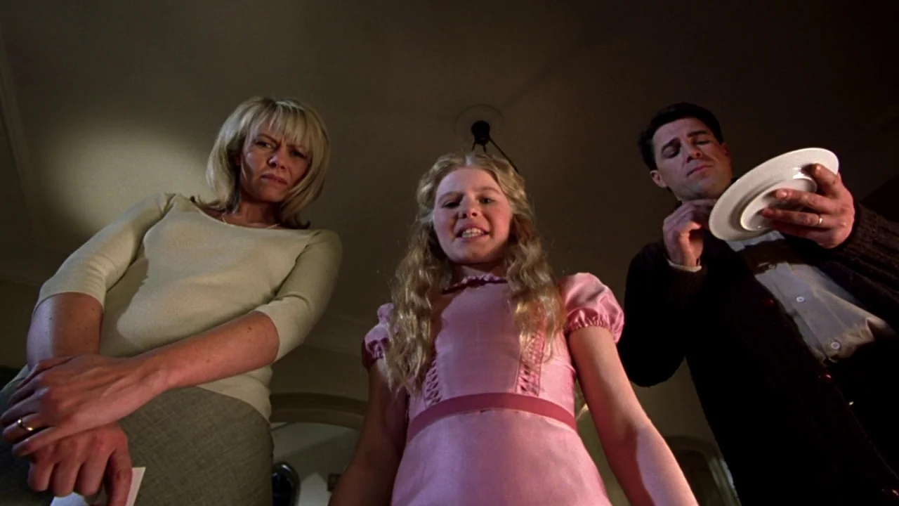 Seed of Chucky (2004) movie still: medium — Three individuals loom over the camera in a darkened room at night. A young girl stands between a woman…