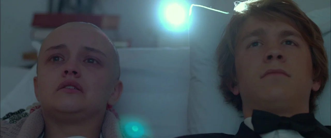 Me and Earl and the Dying Girl (2015) movie still: closeup — A dark bedroom interior features two teenagers lying side-by-side on a bed. They watch…