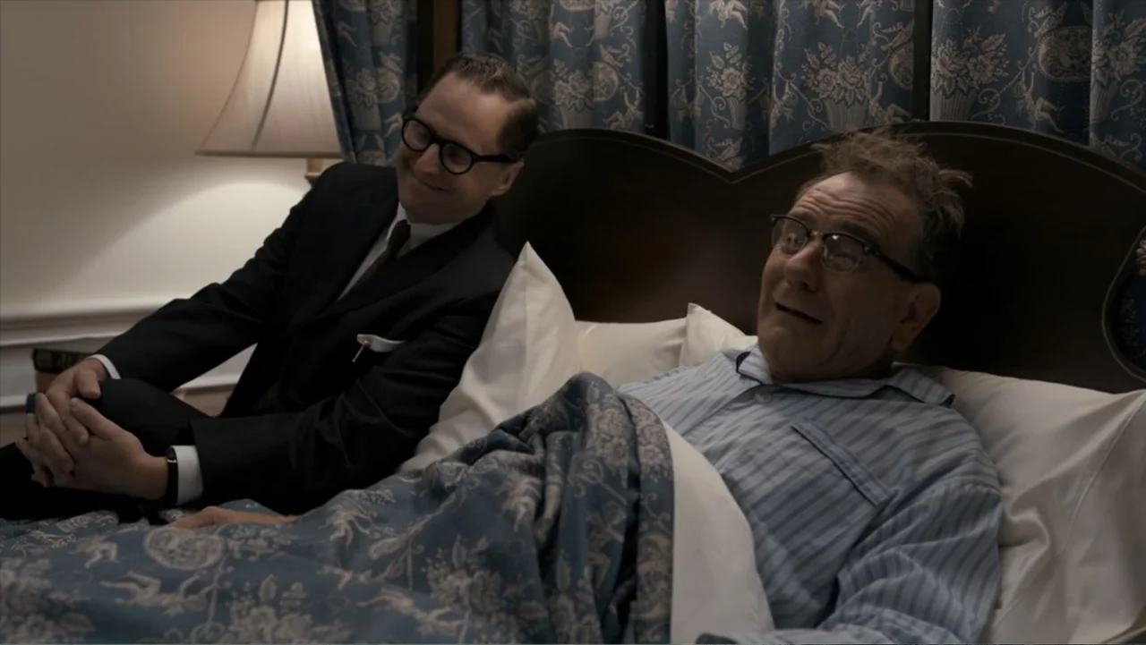 All the Way (2016) movie still: medium — A hotel room with patterned blue curtains and matching floral bedding on the frame. A man in a suit visits…