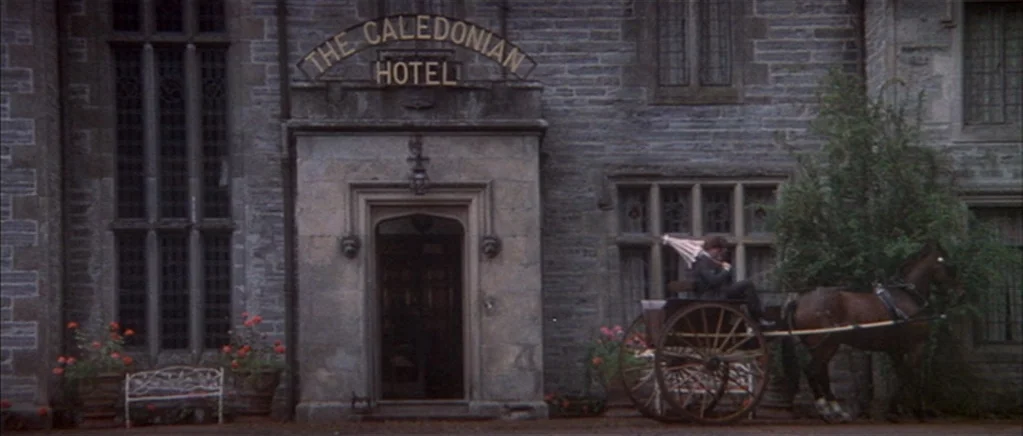 The Private Life of Sherlock Holmes movie still: wide — An old stone hotel building features a sign reading The Caledonian Hotel above the entrance.…