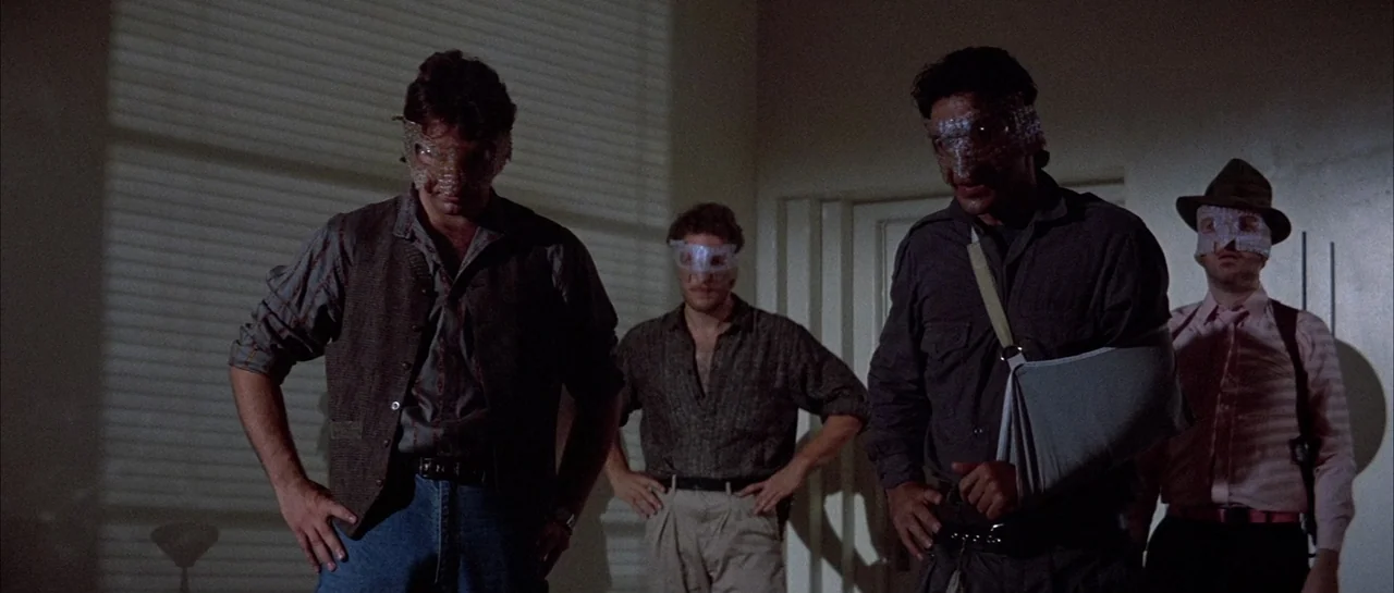 The Adventures of Buckaroo Banzai Across the 8th Dimension (1984) movie still: fullbody — Four men stand side by side in a dimly lit interior room.…