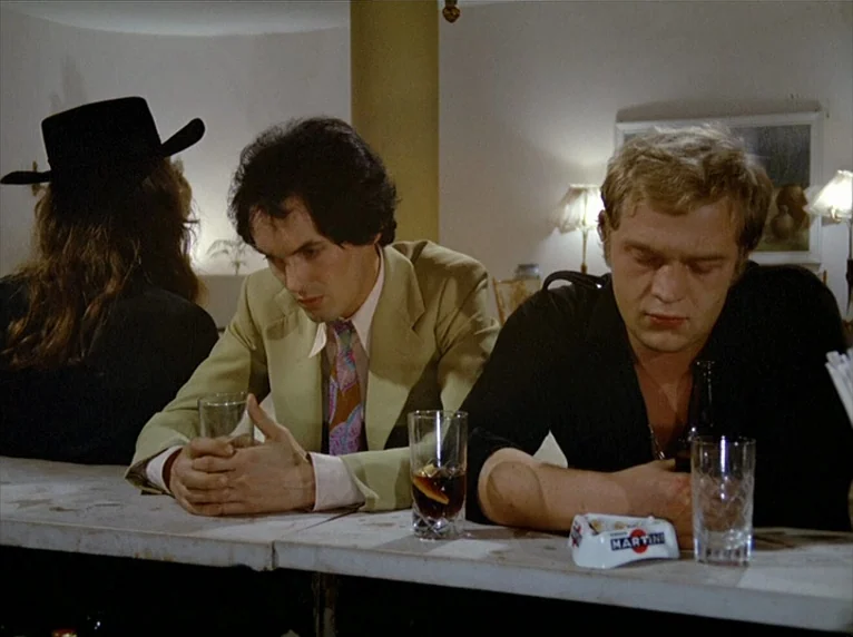 Beware Of A Holy Whore (1971) movie still: medium — A dimly lit bar with a white counter and several drinking glasses. Two men sit at the counter…
