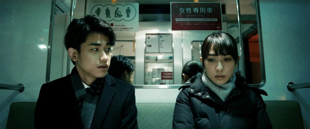 To Hear the Birds Singing (1995) movie still: medium — The interior of a clean modern commuter train car features green bench seating. A young man…
