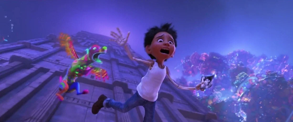 Coco (2017) movie still: medium — A boy and a colorful winged creature fall vertically past a massive stone structure. The background is a vast…