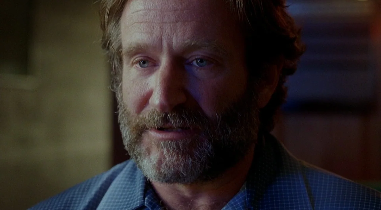 Good Will Hunting (1997) movie still: closeup — A dimly lit indoor space with blurred background textures suggesting a tavern or pub. The man is…