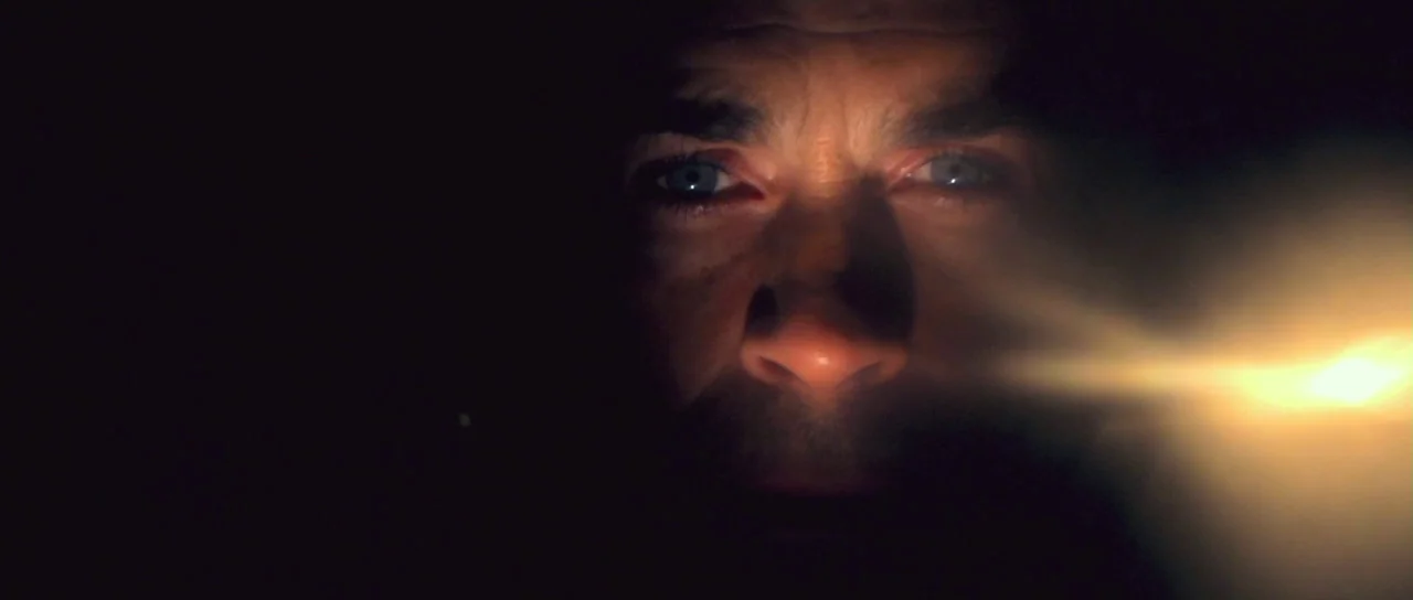 I Melt With You (2011) movie still: closeup — A man's face emerges from total darkness into a bright light. The light creates a significant…