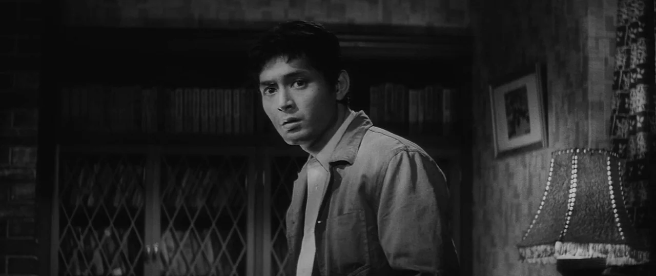 The Human Condition I: No Greater Love (1959) movie still: medium — A dimly lit room with patterned wallpaper, a bookshelf with lattice glass doors…
