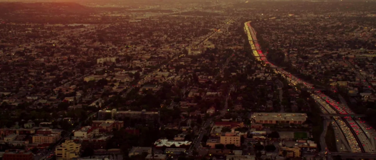 The Purge: Anarchy (2014) movie still: establishing — An aerial view of a sprawling city landscape at dusk with grid-like streets. A major highway…