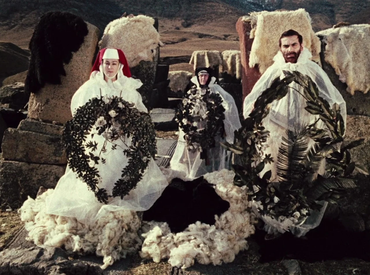 The Colour of Pomegranates (1969) movie still: fullbody — Three individuals in white gowns stand on a desolate, hilly landscape with stone…