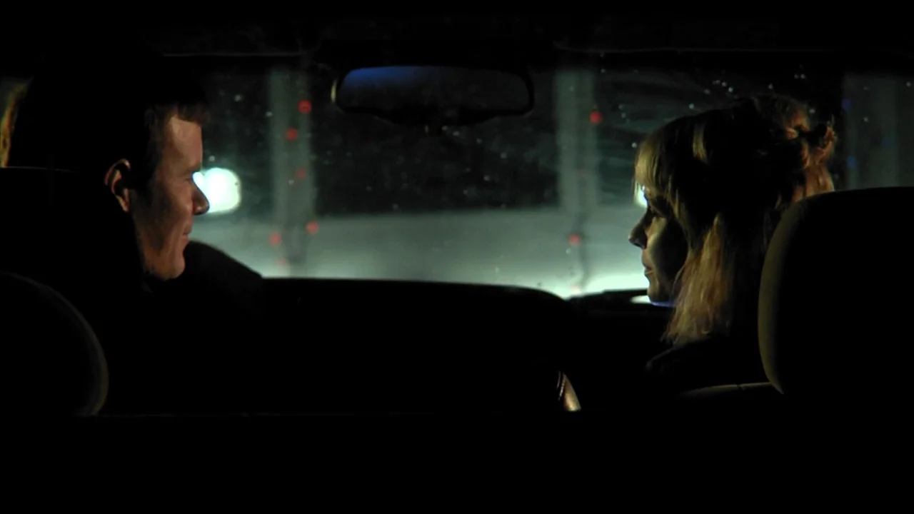 A Horrible Way To Die (2010) movie still: medium — The interior of a moving car at night with silhouettes visible against the windshield. A man and…