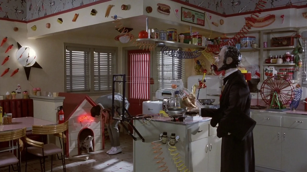 Pee-Wee’s Big Adventure (1985) movie still: wide — A whimsically decorated kitchen features patterned wallpaper and various hot dog themed wall…