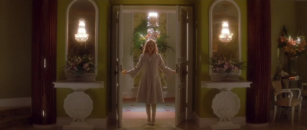 Where The Truth Lies (2005) movie still: fullbody — A symmetric interior hallway features lime green walls with ornate white shell pedestals. A…