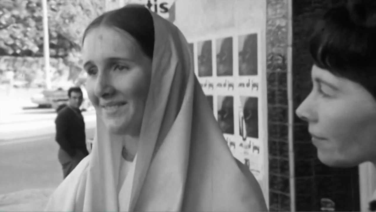 Hare Krishna! The Mantra, the Movement and the Swami Who Started It All (2017) movie still: medium — Two women stand on a sidewalk near a building…