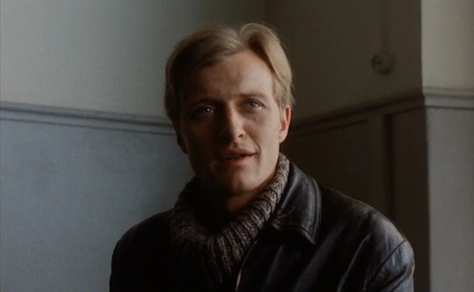 Soldier of Orange (1977) movie still: closeup — A man stands in an interior hallway with light blue painted walls. He looks towards the side while…