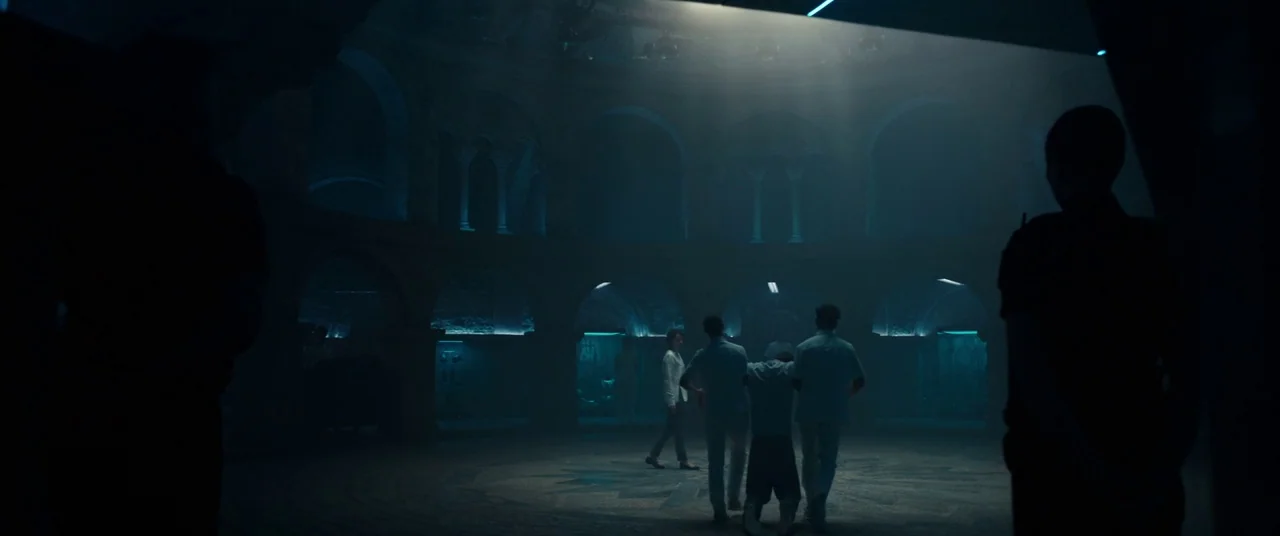 Assassin’s Creed (2016) movie still: wide — A vast circular room features stone arches and a central mosaic on the floor. Two people guide a…