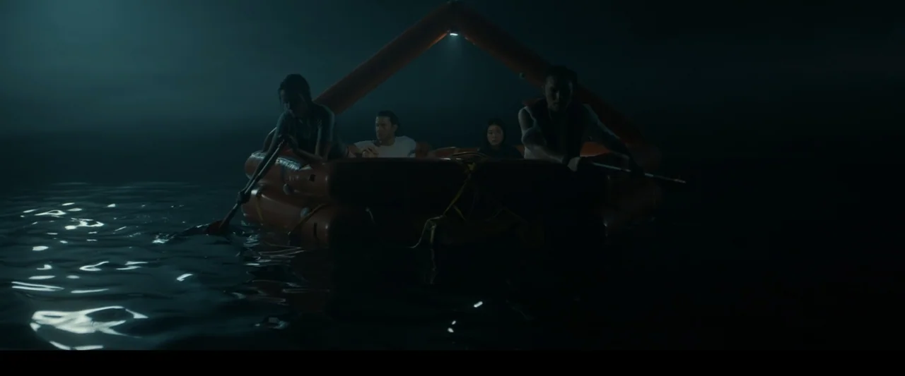 Great White (1998) movie still: medium — An orange inflatable life raft floats on dark, calm open water at night. Four individuals sit inside the…