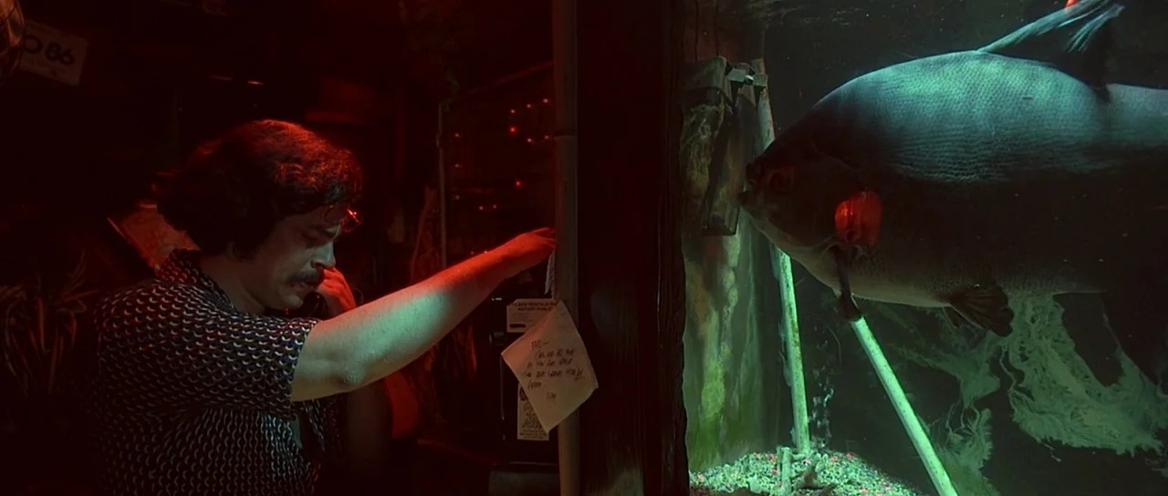 Fear and Loathing In Las Vegas (1998) movie still: medium — A dark, dimly lit bar space is filled with intense red and green light. A man holds a…