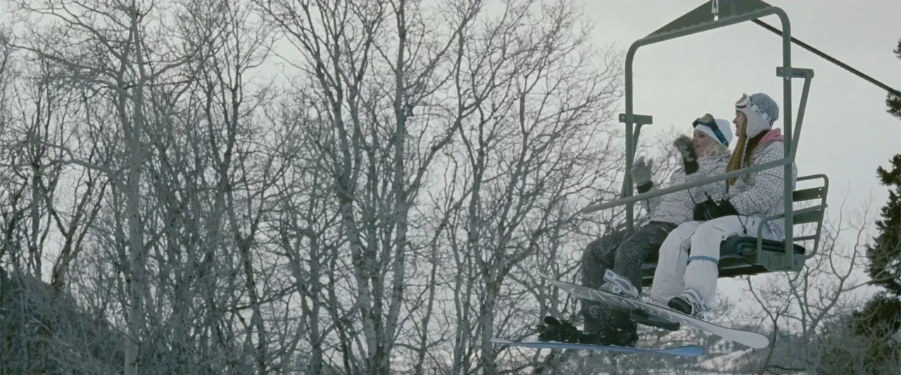 Frozen (2010) movie still: medium — A snowy mountain side with leafless trees stands behind a metal ski chairlift. Two young women sit together in…