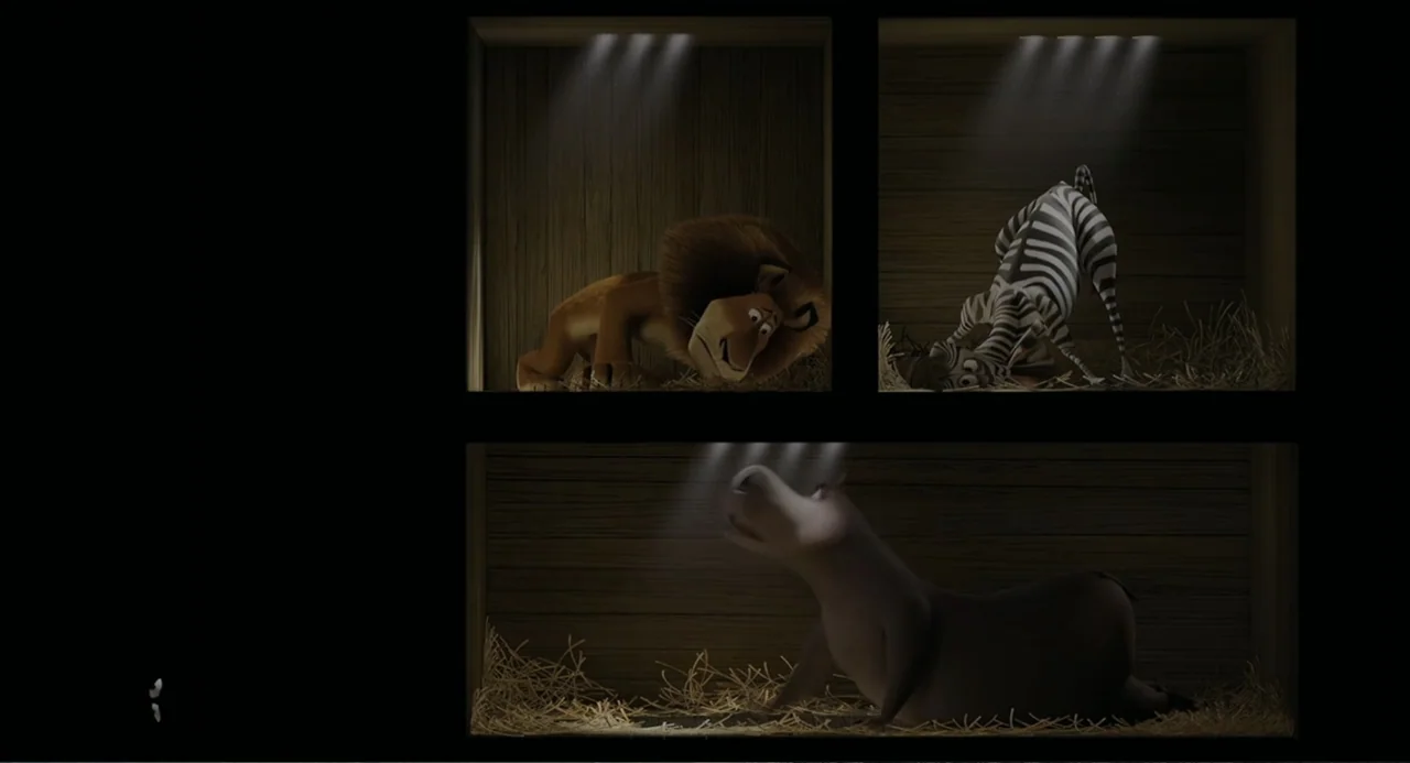 Madagascar (2005) movie still: wide — Three separate wooden stalls house animals in a dimly lit environment with straw bedding. A lion, a zebra, and…