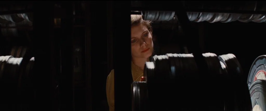 Inglourious Basterds (2009) movie still: medium — A dark space features rows of industrial metal shelving packed with circular film canisters. A…