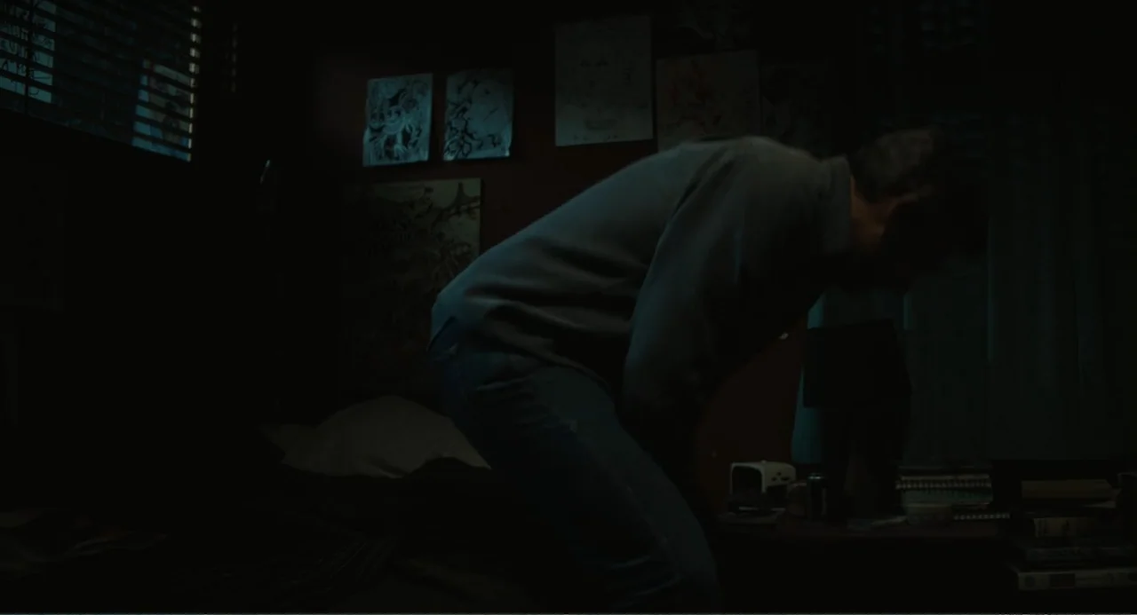 Beautiful Boy (2011) movie still: medium — A dark bedroom with drawings pinned to the wall and a cluttered bedside table. A man in a shirt and jeans…